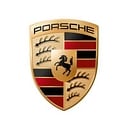 Logo Porsche : Signification et Détails du Blason Doré Logo Porsche doré en forme de blason avec cheval cabré noir, bois de cerf et bandes horizontales rouges et noires.